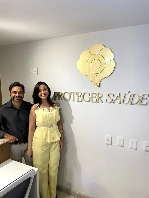 Recepção da clínica, com o nome Proteger Saúde em dourado na parede